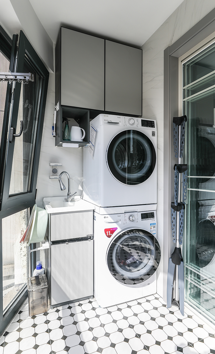 陽臺是晾曬衣物的場所，一側洗衣機和烘干機上下放，一側為洗衣池，白色的藝術地磚加上落地窗，讓陽光柔和的照進來，很舒適、很愜意。