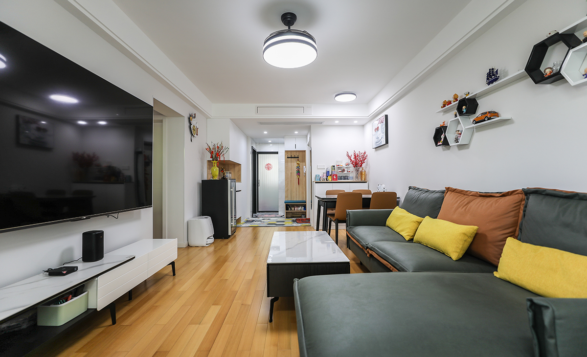 客廳開間較長，80寸電視機(jī)在家里就能體驗(yàn)影院般的效果，空間也很寬闊、裝飾柜采用暖白色門板，增加亮度，吊頂造型上采用雙眼皮吊頂。地面采用橡木色地板。造型和色調(diào)上無不給人以簡潔、大氣、時(shí)尚的感覺。