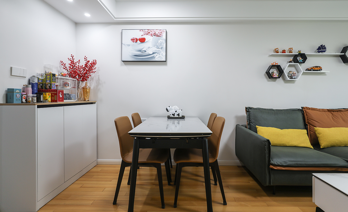 餐廳餐桌搭配餐邊柜，既實(shí)用、又有裝飾功能，頂上筒燈增加氛圍感，墻面一幅裝飾畫把餐廳點(diǎn)綴的很有生機(jī)，巖板餐桌把用餐硬度高又好打理，放油抗污，地面同客廳地板通鋪，整體色彩和造型上都簡潔大氣。
