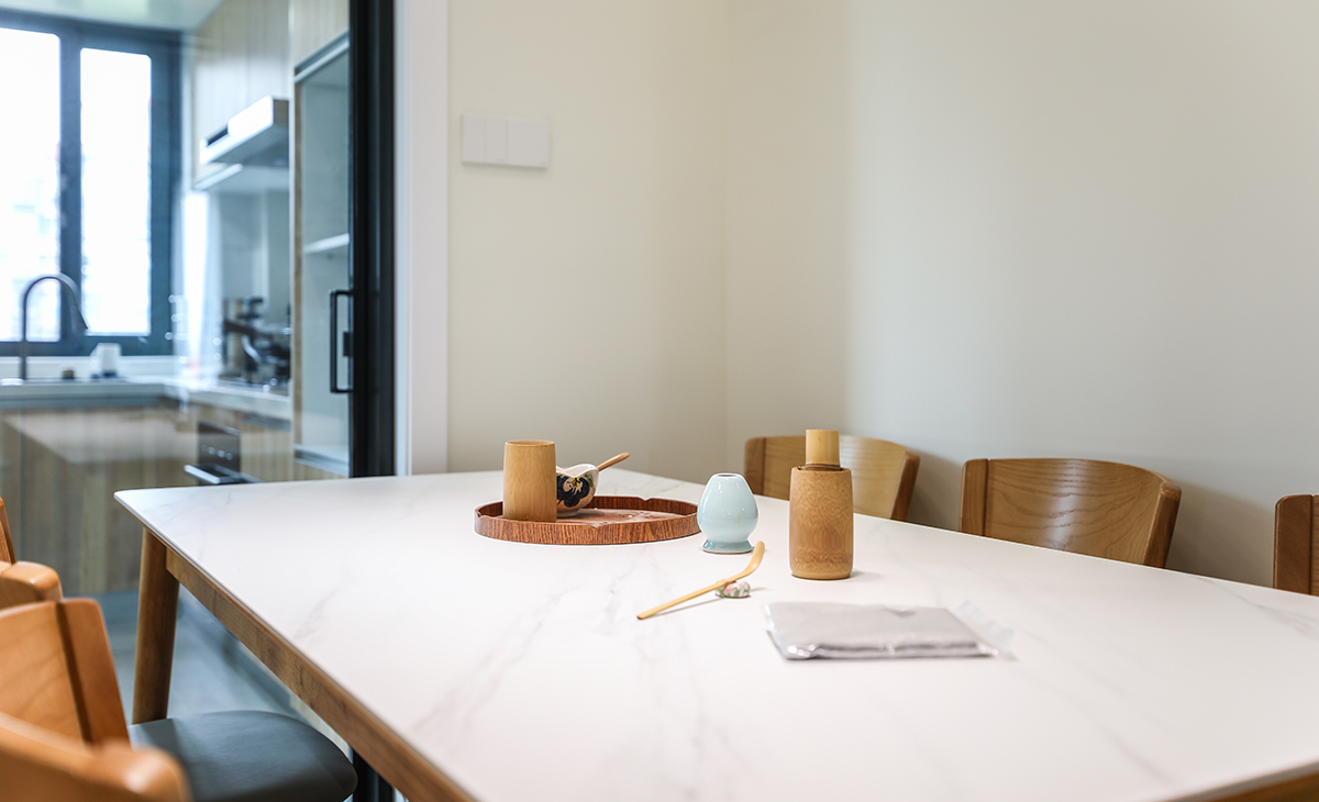 餐桌使用巖板臺面，原木色的椅子和整體風格融為一體，空間自然協調，簡潔大氣，頂上雙眼皮圍邊吊頂凸顯了現代極簡風格的高端大氣。采用明裝軌道燈。
