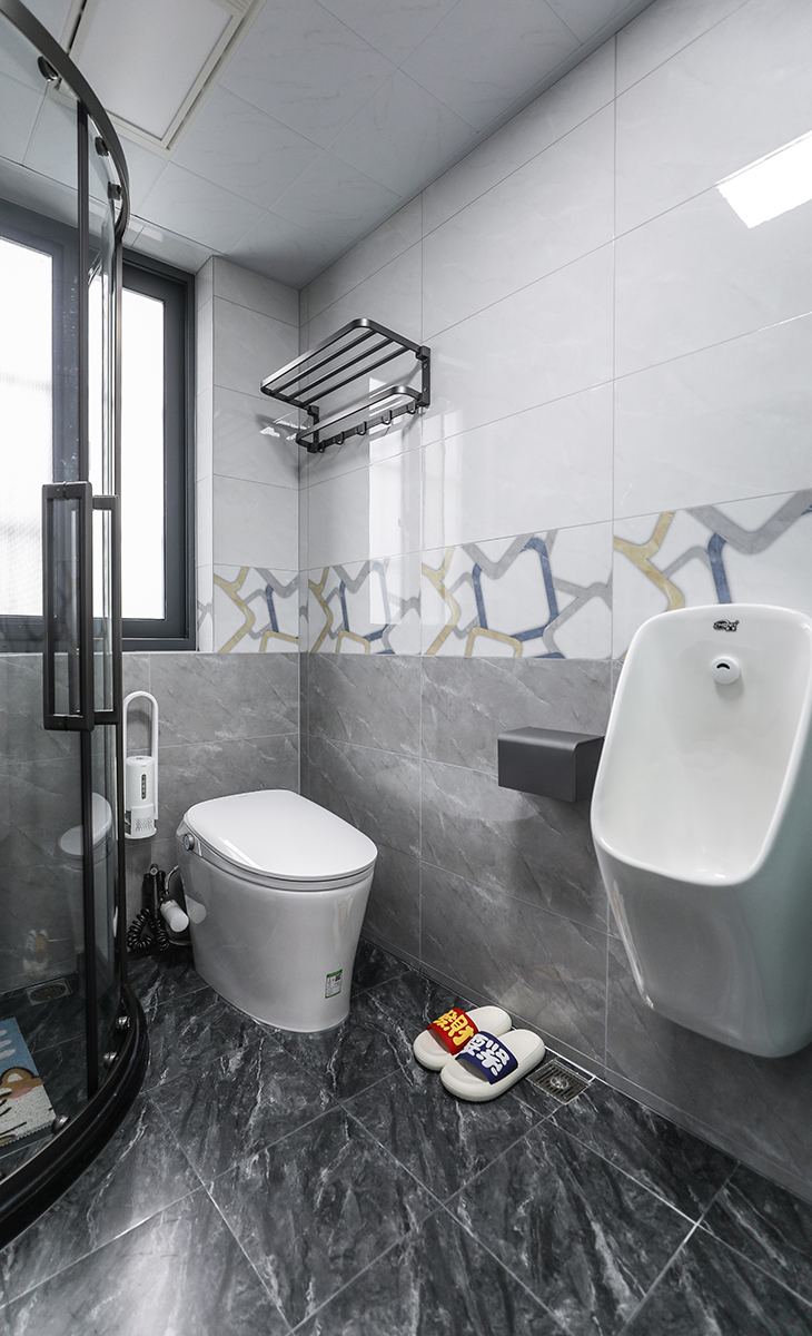 墻磚到地磚選擇的是同花色由淺到深的大理石磚，無水箱馬桶、掛式小便斗，處處體現了男主是穩重、注意個人衛生的奮進青年。