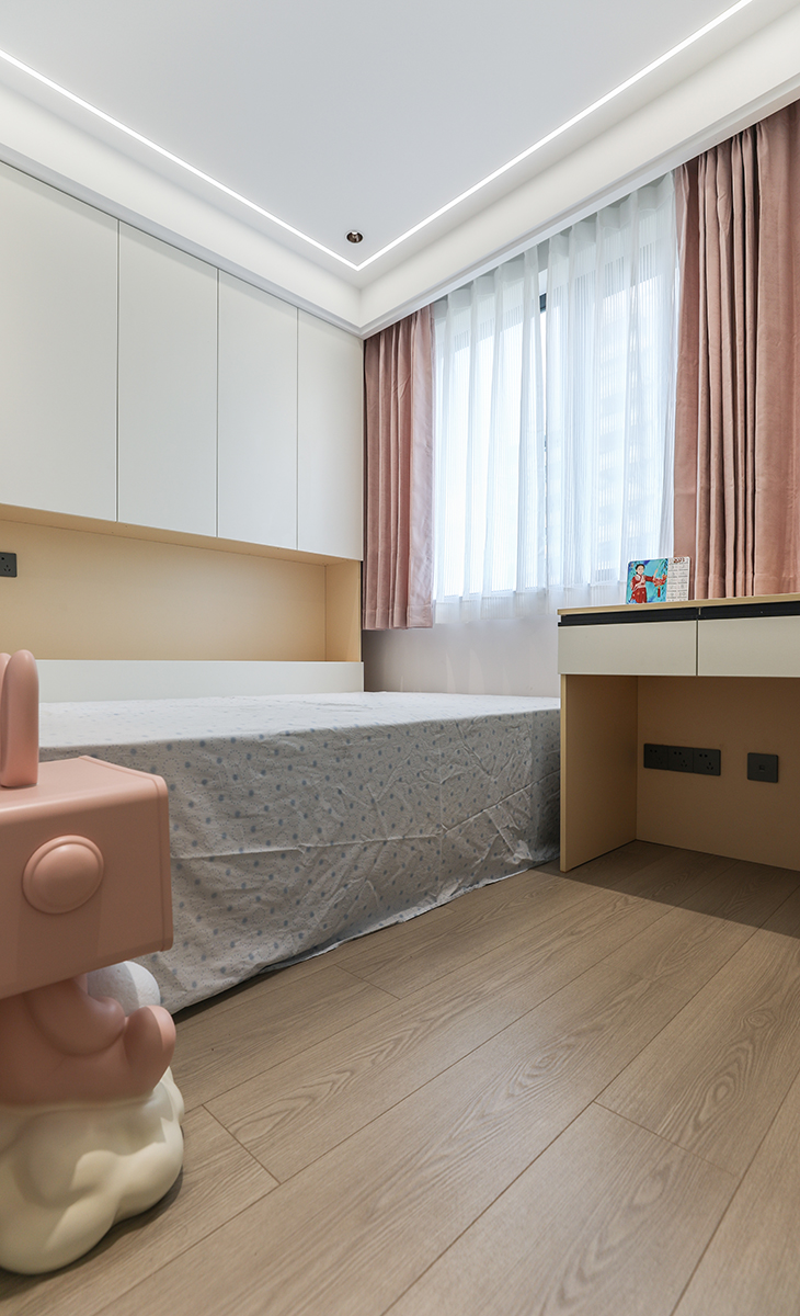 女孩房的色彩相對偏暖，通過改變軟裝的搭配，選擇粉紅窗簾和粉色床頭柜，讓整個空間顯得溫馨浪漫。淡妝濃墨總相宜，色調的改變更加讓主人的小女兒充滿向往，圓了小女孩的一個新居夢。