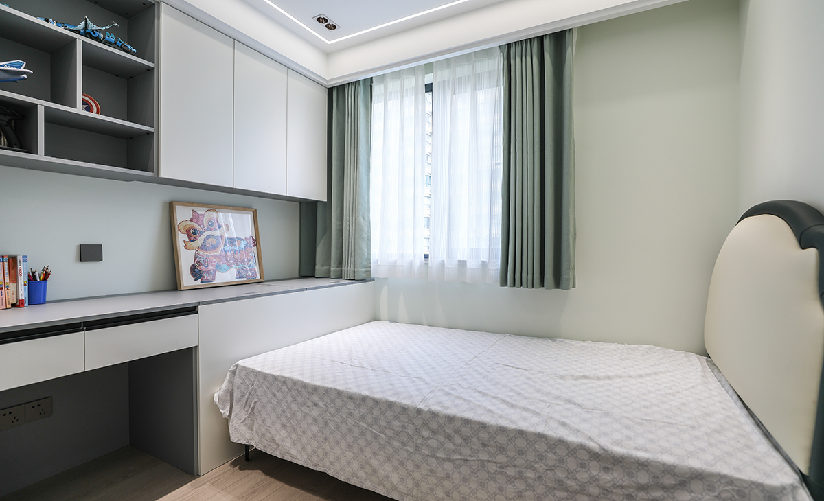  男孩房的頂面不再是傳統的一個主燈，而是改為一圈線燈和筒燈的結合，打破傳統，突破局限，營造了一個明亮且線條感更強的氛圍，床尾的定制吊柜和寫字桌，上下對應，給孩子創造了一個獨立的學習和娛樂空間。
