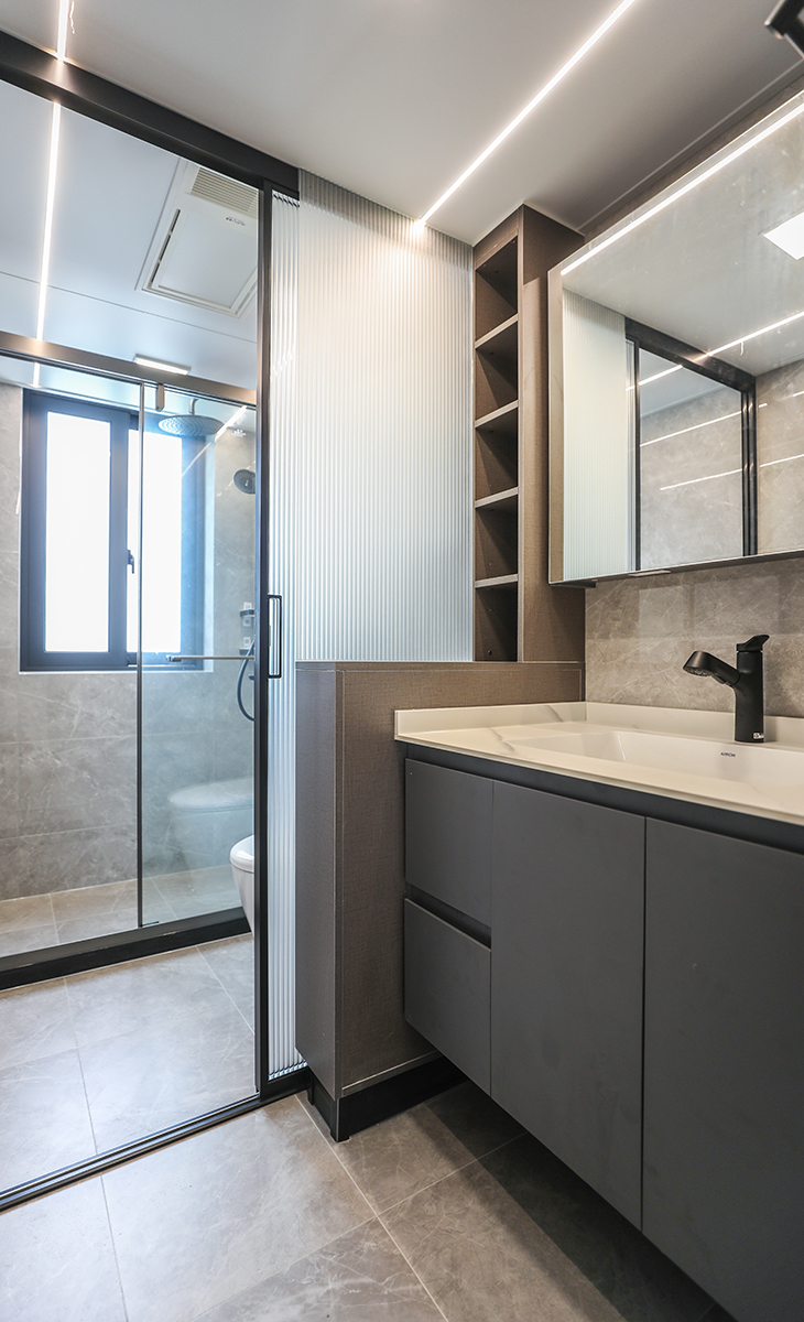 位于通道上的客衛生間，采用了干濕分離的設計，將空間合理劃分。通過防水柜體與長虹玻璃組合來進行隔斷，增加收納的同時也將空間延伸，吊頂采用小方燈加線燈的組合，更具線條美。