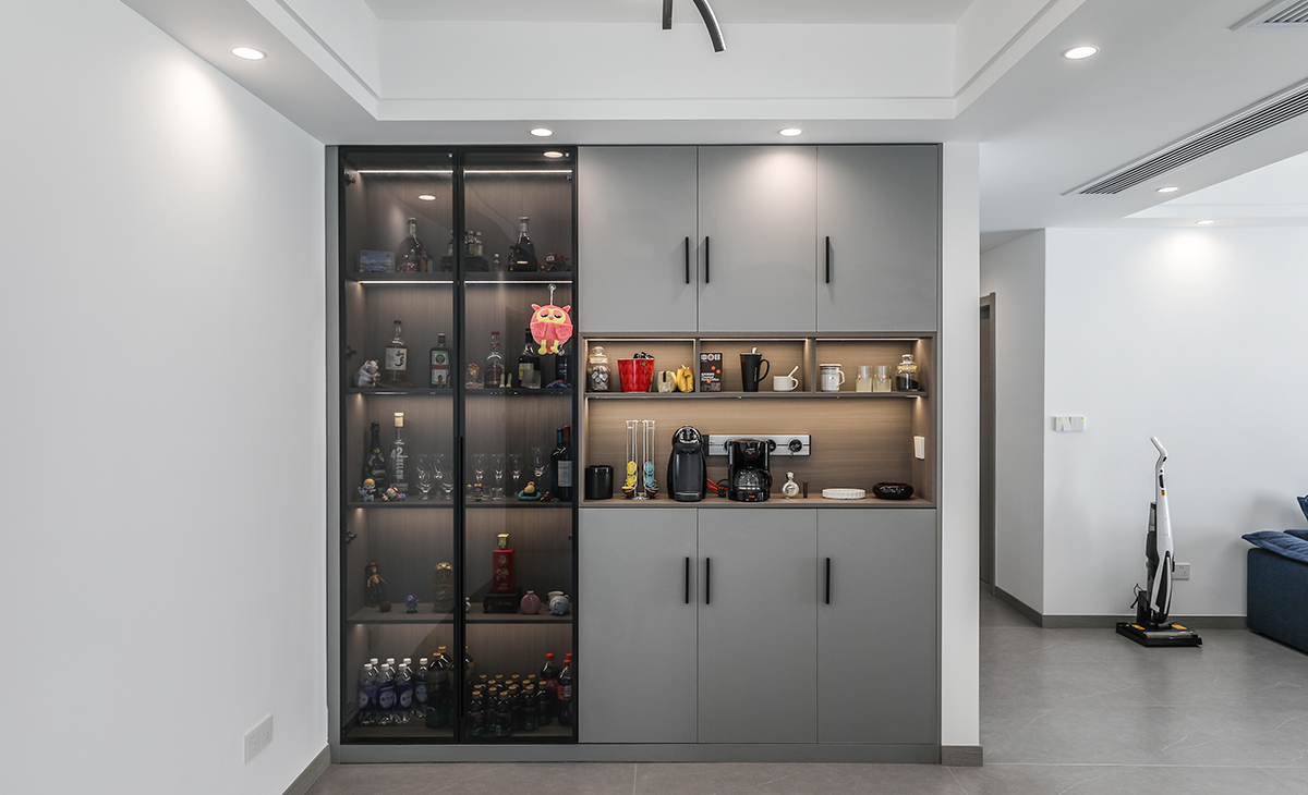 靠著門廳和鞋柜做一排背靠背的餐邊柜，既實用、又有裝飾功能，深灰色框架，極窄邊框玻璃門和淺灰門板相呼應，巖板餐桌把用餐氛圍調和的很溫暖，淺灰色柔光地磚很干凈，色彩和造型上都簡潔大氣。