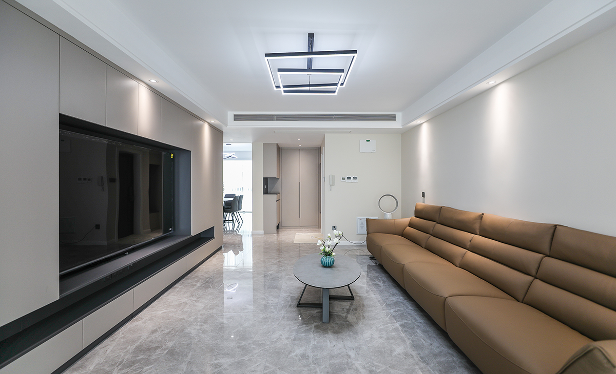 客廳開間很大，滿面電視柜非但沒有讓空間顯得壓抑，反而看起來很大氣，門口的組合柜，沒有因為都是柜子顯得單調(diào)，反而又一次拉長了空間，公共區(qū)域滿鋪750*1500的大磚，縫隙更少，整套裝修都以簡潔的線條為主，不過多修飾，反而還原了裝修本身的意義，舒適，減少衛(wèi)生死角，滿足一家人多口所有儲物需求。