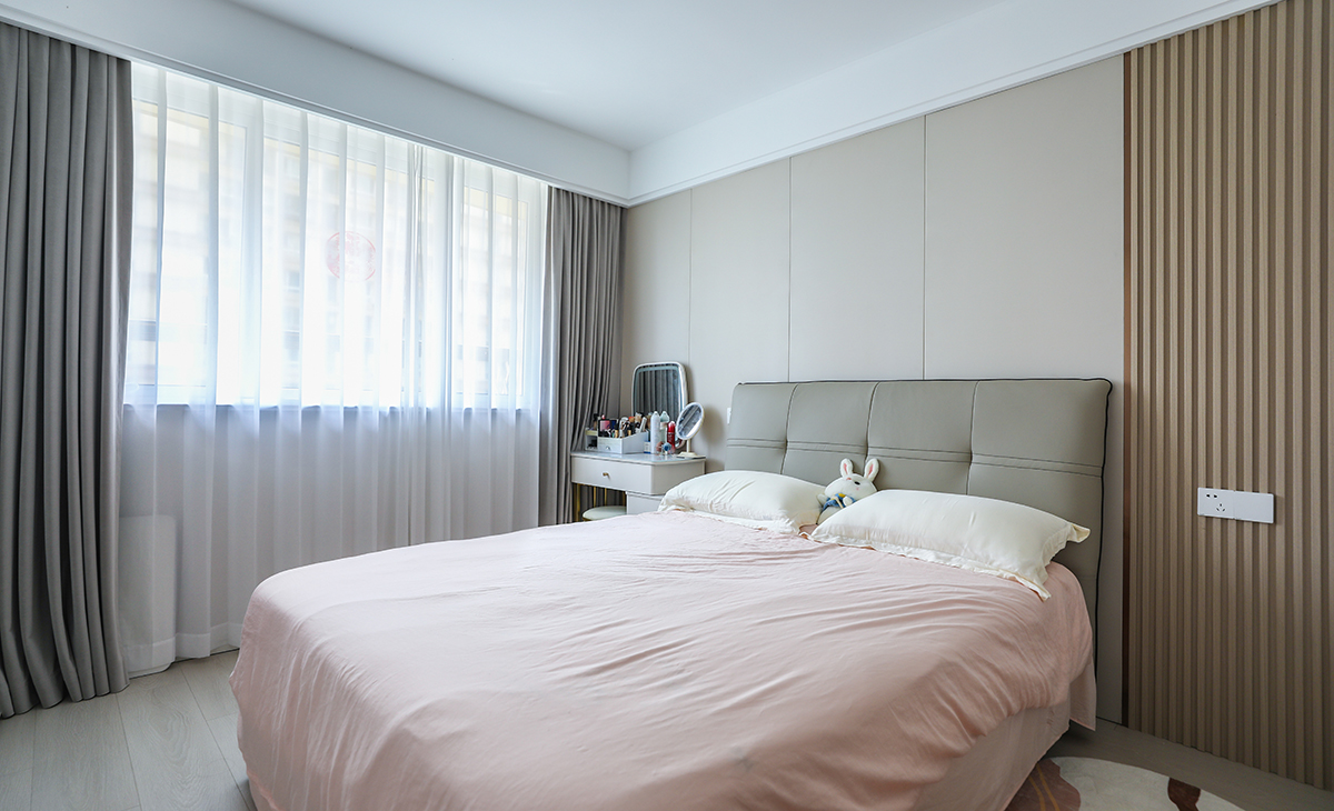 主臥床頭背景和客廳沙發(fā)背景一樣采用了同材質來裝飾，做到了統(tǒng)一風格以及色系。地板選用淺色系的灰木紋地板，再配上同色系的床來搭配。讓整個空間顯得干凈簡潔。