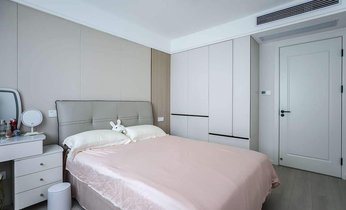 主臥床頭背景和客廳沙發(fā)背景一樣采用了同材質來裝飾，做到了統(tǒng)一風格以及色系。地板選用淺色系的灰木紋地板，再配上同色系的床來搭配。讓整個空間顯得干凈簡潔。