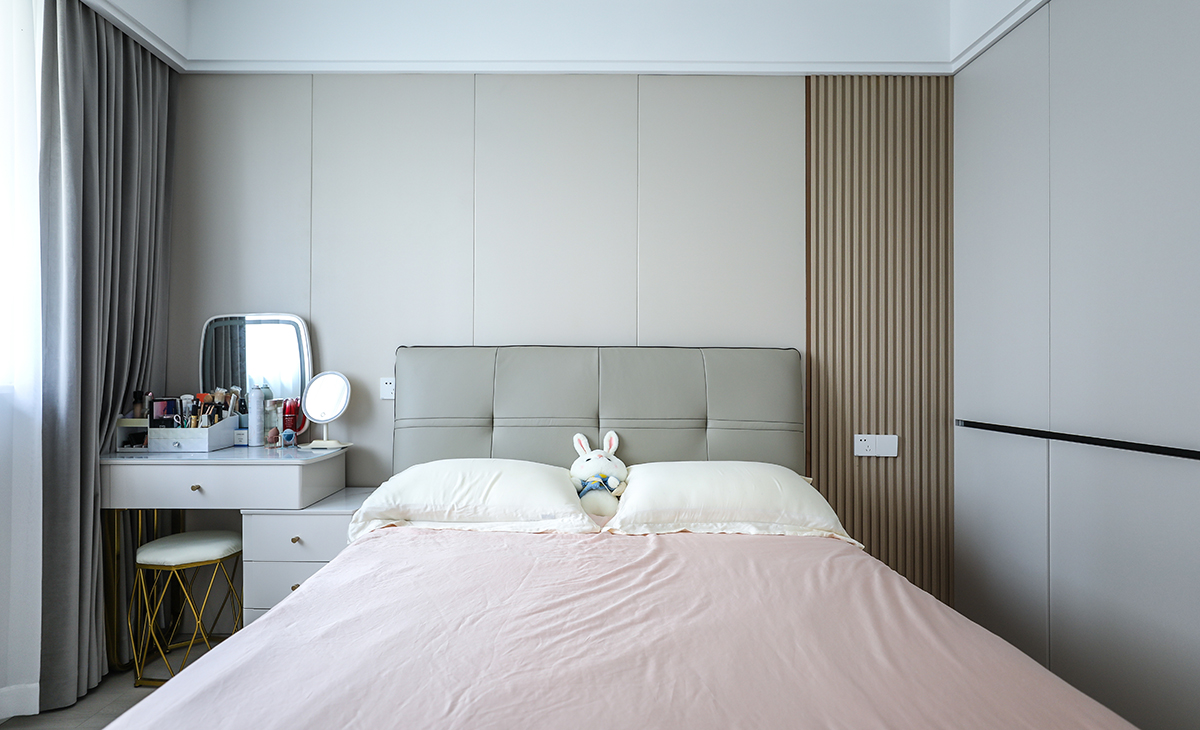 主臥床頭背景和客廳沙發(fā)背景一樣采用了同材質來裝飾，做到了統(tǒng)一風格以及色系。地板選用淺色系的灰木紋地板，再配上同色系的床來搭配。讓整個空間顯得干凈簡潔。