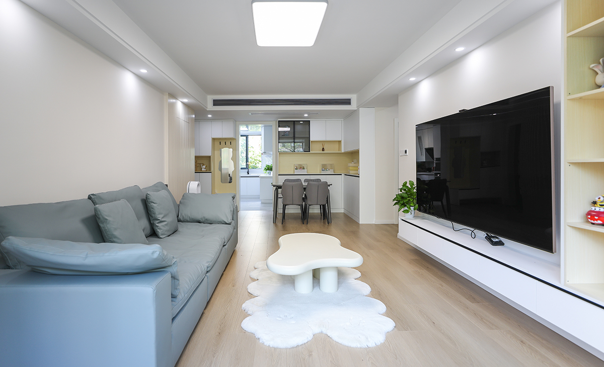 客廳的色彩搭配為墻淺地深的配色理念，這樣對于整體性有不可忽視的效果，沙發(fā)的背面做了木格柵裝飾，讓原本單調(diào)的墻面有了生機(jī)。