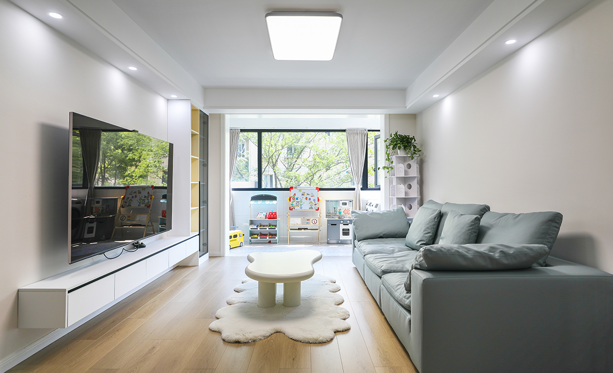 客廳的色彩搭配為墻淺地深的配色理念，這樣對于整體性有不可忽視的效果，沙發(fā)的背面做了木格柵裝飾，讓原本單調(diào)的墻面有了生機(jī)。