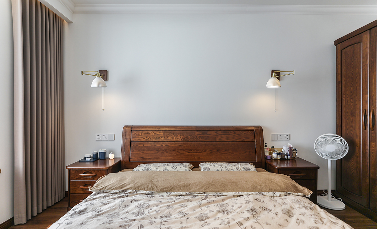 主臥床頭背景白色，地面用胡桃色，L型大飄窗讓臥室空間具有延伸感，壁燈把整個空間點綴地豐富、有內涵。