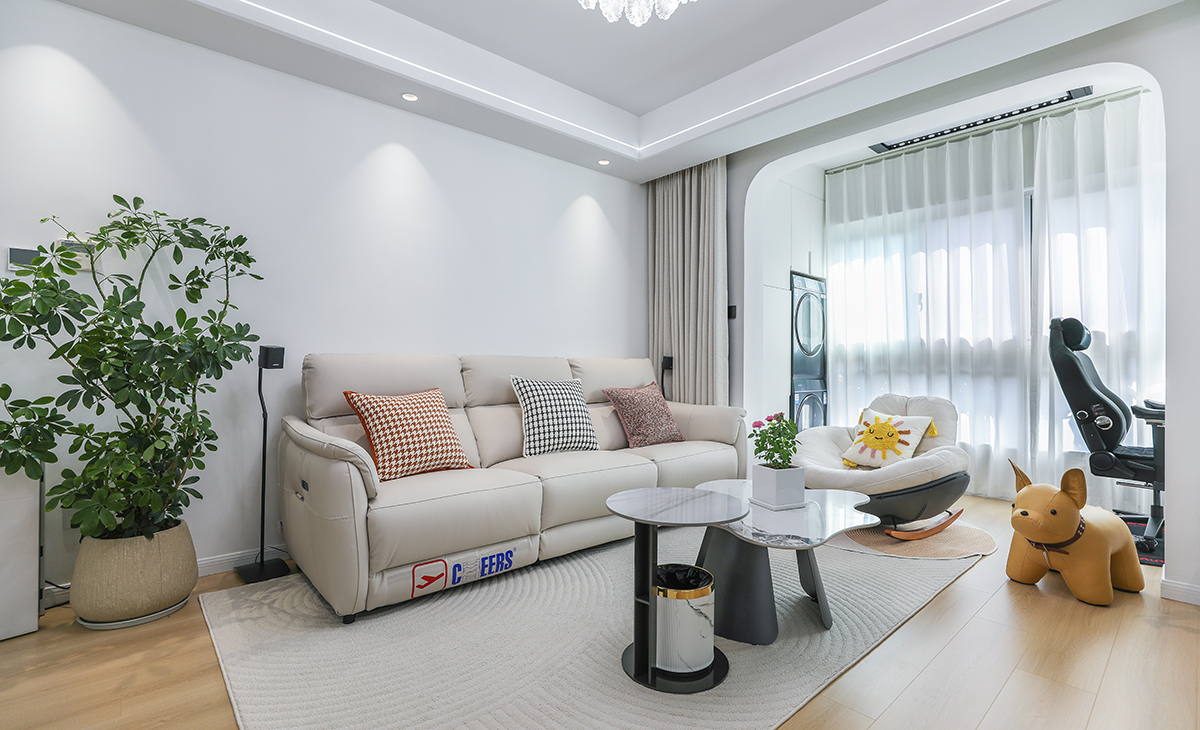 沙發(fā)背景刷米白色涂料，米色的沙簾，沙發(fā)背景留白設(shè)計(jì)，色調(diào)上墻面涂料和窗簾用淺色，沙發(fā)用淺灰色，深淺搭配的錯(cuò)落有致，既溫馨又簡(jiǎn)潔。