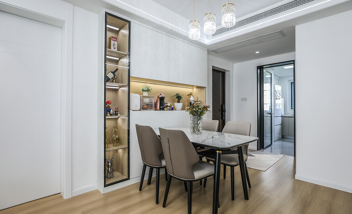 餐廳空間比較方正寬敞，靠墻做一排裝飾柜，既實(shí)用、又有裝飾功能，原木色框架，極窄邊框玻璃門和白色木門板相呼應(yīng)，巖板餐桌把用餐氛圍調(diào)和的很溫暖，原木色地板很干凈，色彩和造型上都簡(jiǎn)潔大氣。