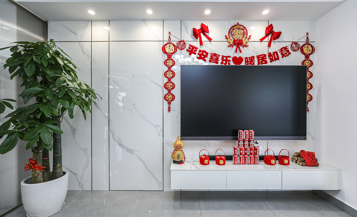 亮光石紋竹木纖維板和極窄線條將房門和背景完美集合，電視柜左邊的裝飾盆景作襯托，巖板臺面電視柜也很大氣，讓空間不但時尚而且清爽。