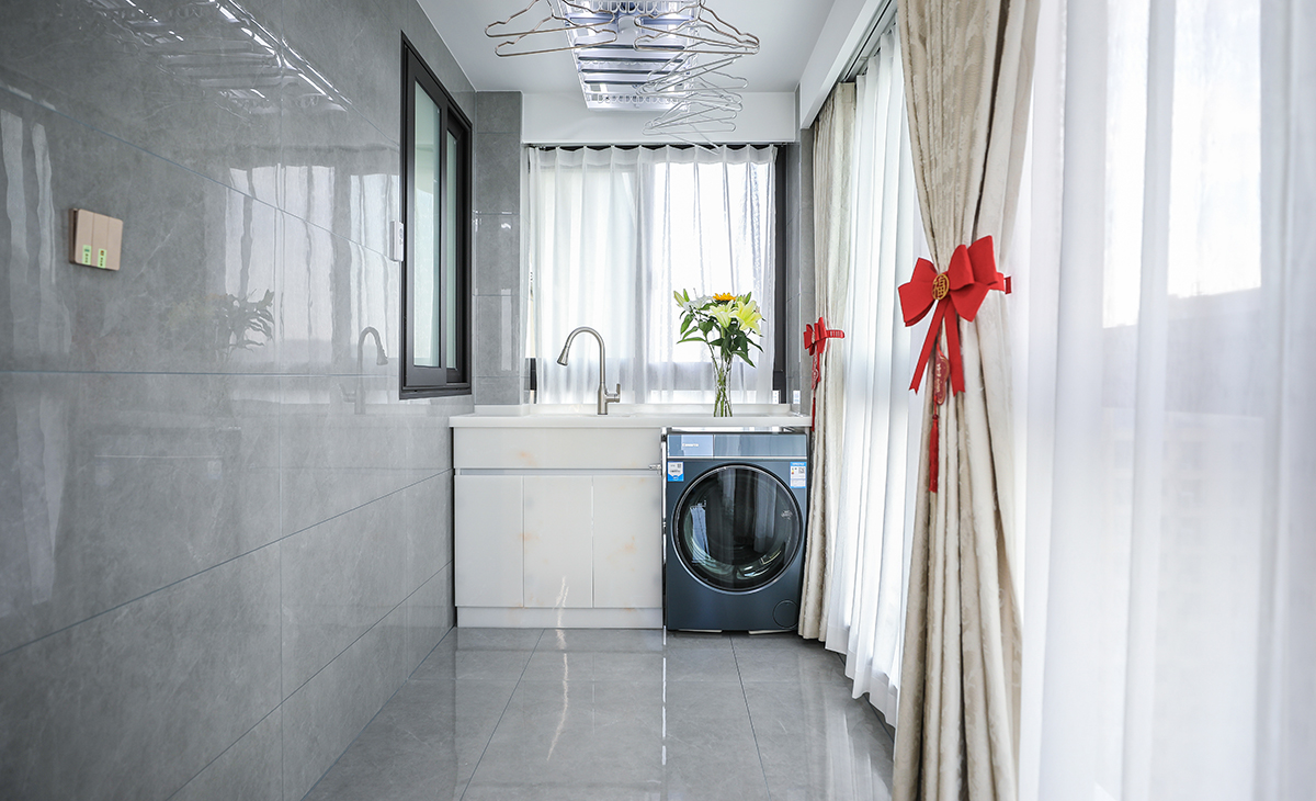 陽臺是晾曬衣物的場所，一側洗衣機和水池，一側為按摩椅，顏色以灰色為主，超大落地玻璃窗讓陽光柔和的照進來，很舒適、很愜意。