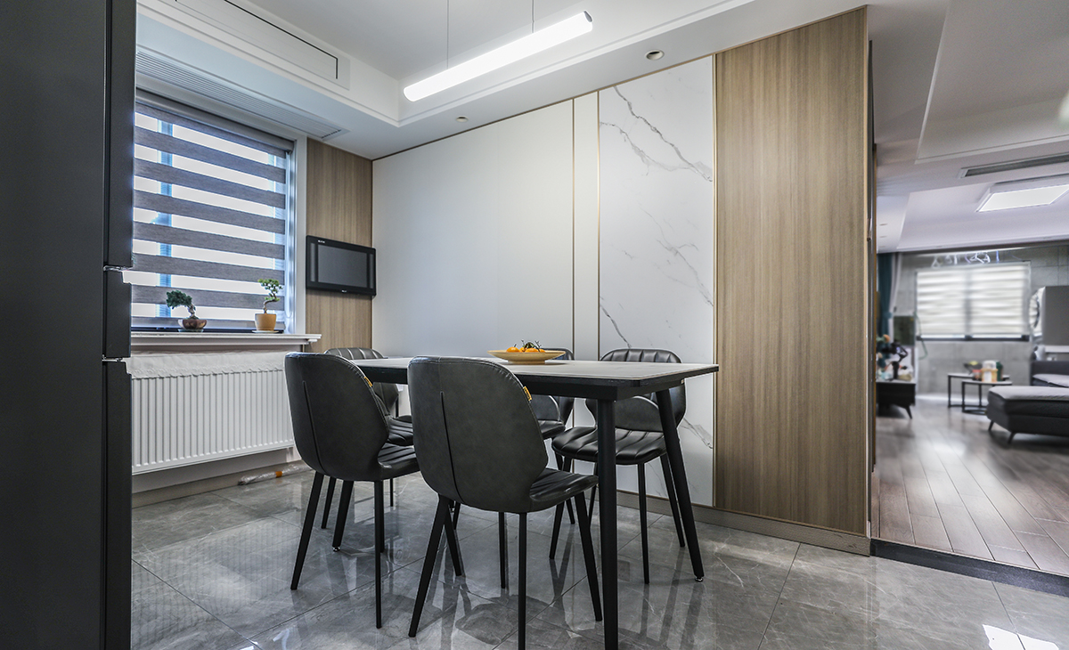 餐廳也做了背景墻，木色和純色大理石紋路的集成墻板做搭配，巖板餐桌把用餐氛圍調(diào)和的很溫暖，讓整個餐廳的空間再得到一個升華，色彩和造型上都簡潔大氣。