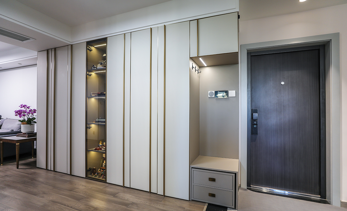 進(jìn)門玄關(guān)處，做了一大排儲藏柜，解決了家中收納少的問題，因?yàn)樵诠矃^(qū)域，為了使整個柜子不那么沉悶，中間加了玻璃門，里面放上展示品，整個空間的格調(diào)一下就上去了。