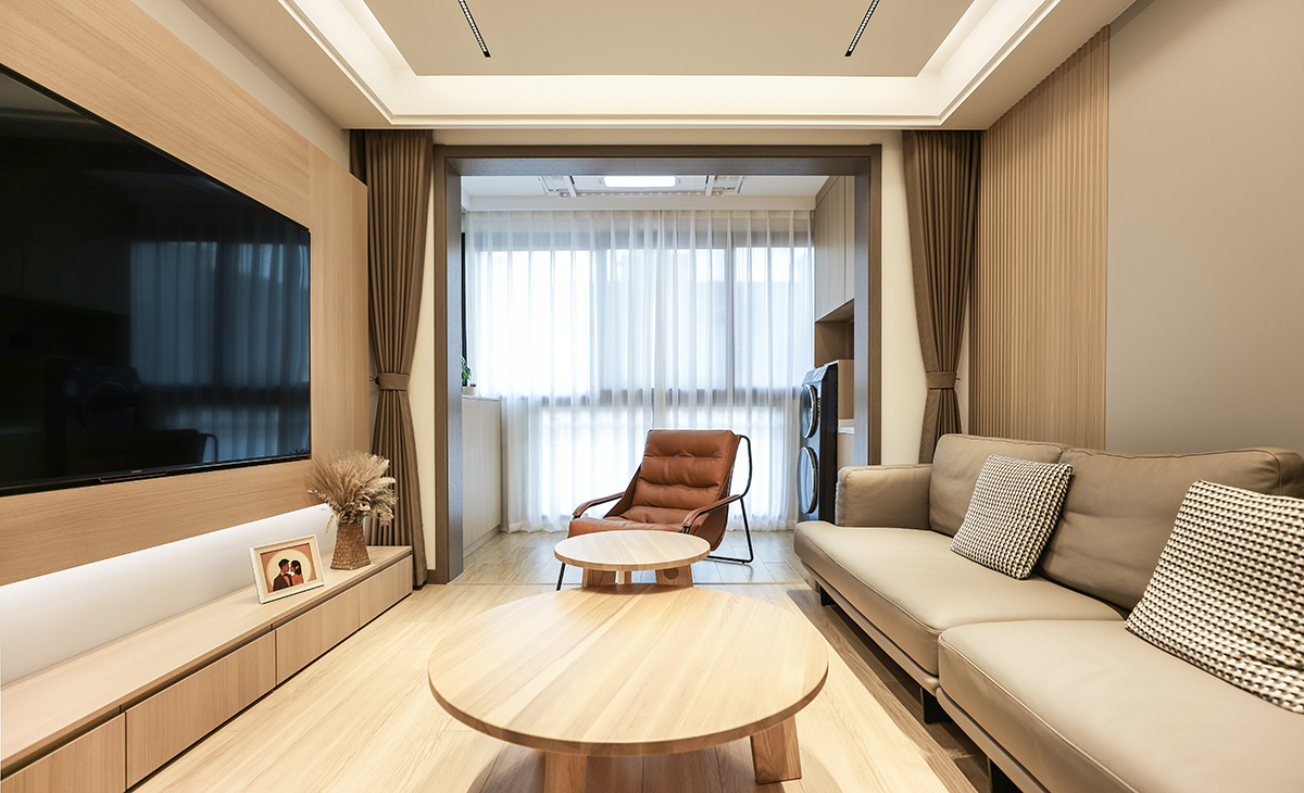 客廳長方形戶型，電視墻以原木色板材凸出來，把電視機嵌入形成一個完成面，底部做線性燈，很有氛圍感，底部用白色涂料更能凸顯整體效果圖。沙發(fā)背景墻左邊以現(xiàn)代流行的格柵為主，右邊墻同樣采用咖啡色木飾面相結(jié)合，沙發(fā)背景墻和電視劇背景墻同樣用兩種顏色和不同造型相結(jié)合，茶幾選的配套原木色餐桌，圓形大小相結(jié)合，再配個咖啡休閑凳子，舒適而愜意。吊頂采用現(xiàn)在很流行的線性無主燈。地面采用原木色地板。整體空間既突出來時尚、簡單、大氣、溫馨的感覺。