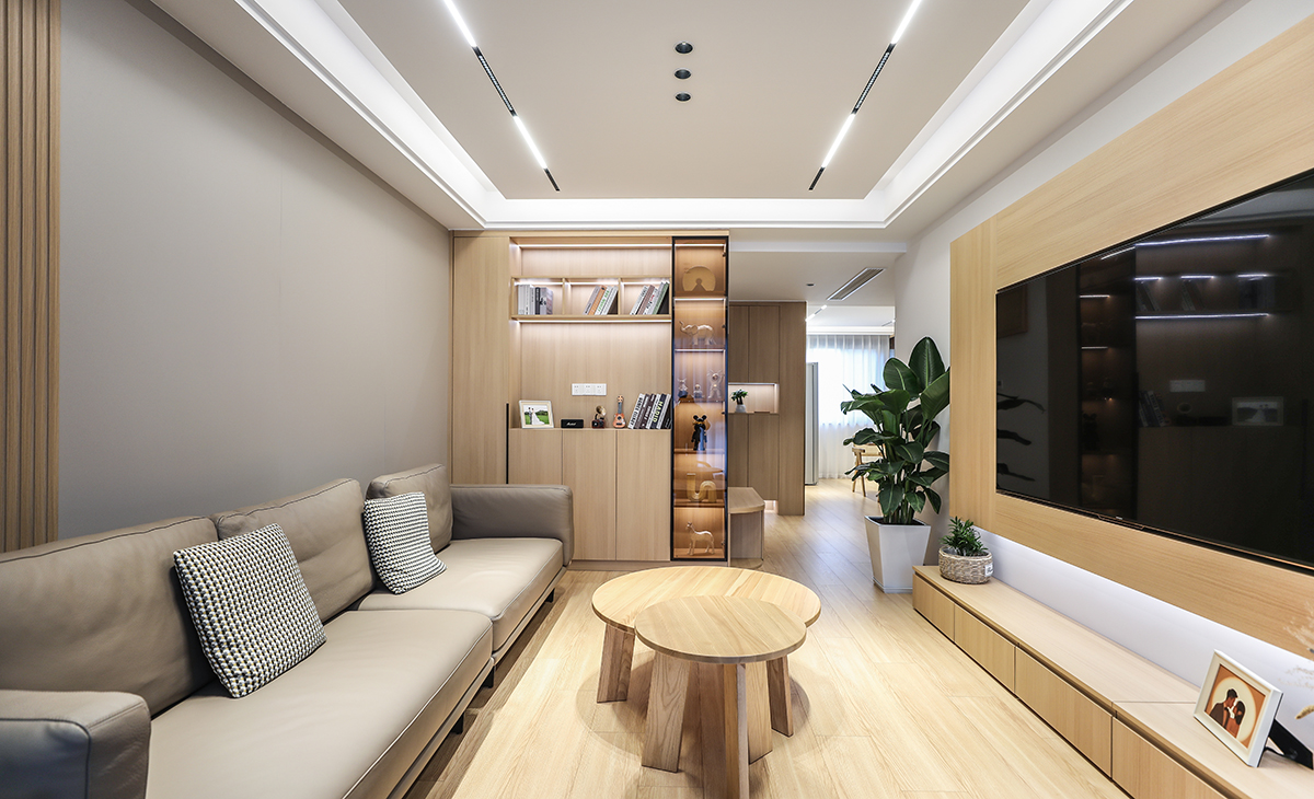 沙發(fā)邊上正好放一個收納柜，原木色的柜體、門板配色黑色玻璃，簡約又時尚，顏色統(tǒng)一，整體安裝線性燈拉長，空間感更時尚、大氣。