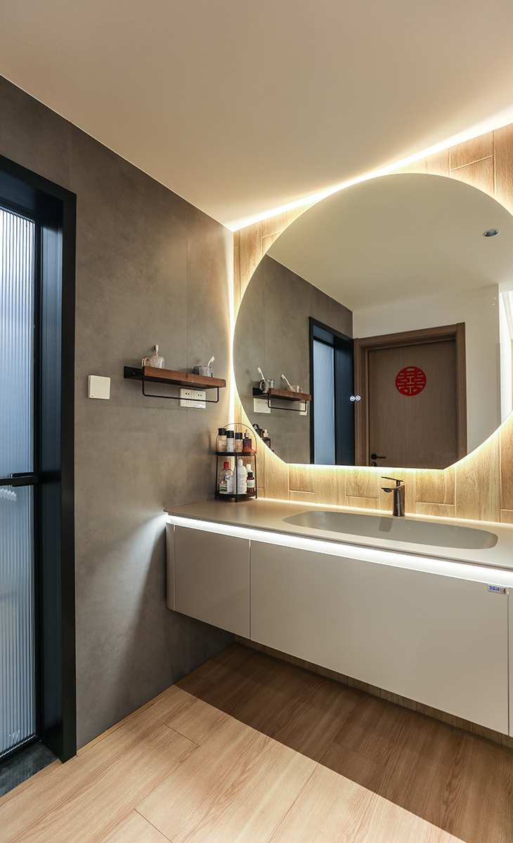 衛(wèi)生間地面鋪600*1200的啞光灰色地磚，直接拿地面磚上墻，整個空間更大氣、明亮，衛(wèi)生間濕區(qū)采用木紋磚，更干區(qū)的臺盆柜墻面顏色統(tǒng)一，地面選用的槍灰色地漏，頂面采用現(xiàn)在流行的蜂窩大板，再配上線性燈和筒燈，讓整個衛(wèi)生間更上檔次和溫馨。淋浴龍頭的位置，做了一個壁龕，分三層，可以平時作為收納功能使用，淋浴房、淋浴龍頭、地漏全部選擇一個顏色，整個顏色統(tǒng)一，更能凸顯原木風(fēng)。