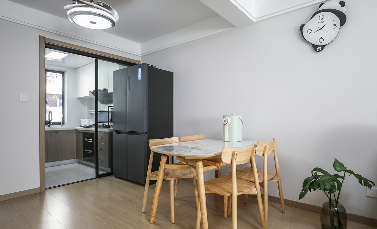 廳空間比較方正寬敞，靠墻做一排裝飾柜，既實用、又有裝飾功能，原木色框架，極窄邊框玻璃門和白色木門板相呼應，巖板餐桌臺面把用餐氛圍調和的很溫暖，原木色地板很干凈，色彩和造型上都簡潔大氣。