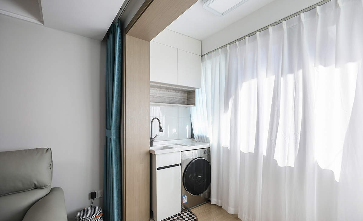 陽臺是晾曬衣物的場所，洗衣機和吊柜，顏色以白色為主，超大玻璃窗讓陽光柔和的照進來，很舒適、很愜意。