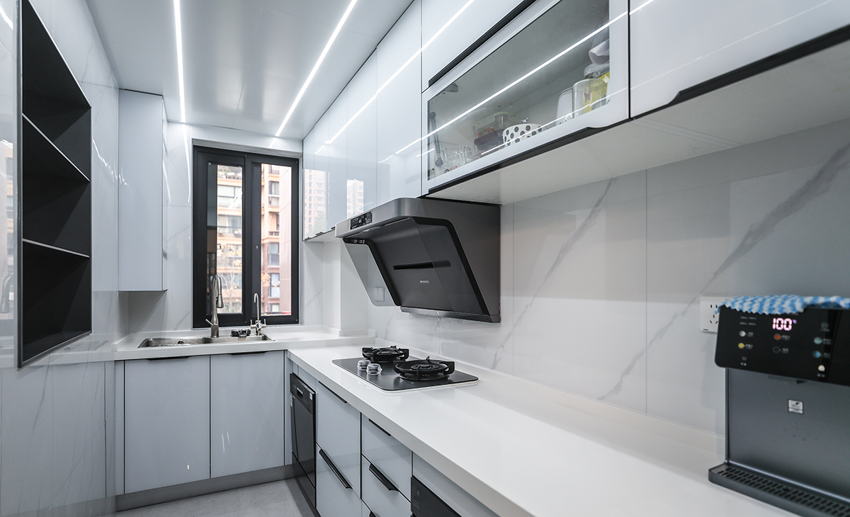 廚房的空間不是很大，做了L型櫥柜，在墻面上做了一個壁龕，增加儲物空間。顏色簡潔明快，材質要干凈和好打理，白色的吊頂和米色的上櫥柜、深色的下櫥柜相呼應，石英石臺面干凈、好打理，各種廚房電器全部配齊，滿足主人制作各種美食的需求。