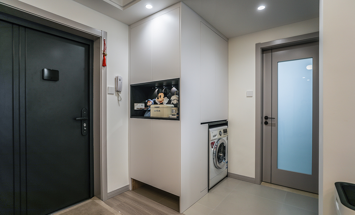 空間整體以暖白色調為主，現代感軟裝與整體空間更加溫馨，陽臺和客廳打通，讓客廳空間變的更通透，進門處鞋柜和洗衣柜結合一體及美觀也增加了收納。