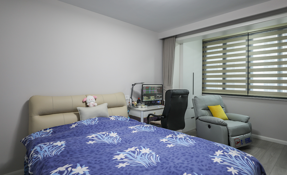 整個臥室的顏色搭配非常協調。床上的被子和毛絨玩具熊是藍白相間的，這種顏色搭配讓人感到寧靜。床頭的顏色是米色，與整個房間的色調非常協調，給人一種溫馨的感覺。墻壁是白色的，這種顏色增加房間的明亮感，讓整個空間更加開闊和舒適。窗戶上安裝了遮光簾，阻擋陽光的直射，同時也可以讓室內保持舒適的溫度。整個房間的顏色搭配非常協調，給人一種溫馨舒適的感覺。