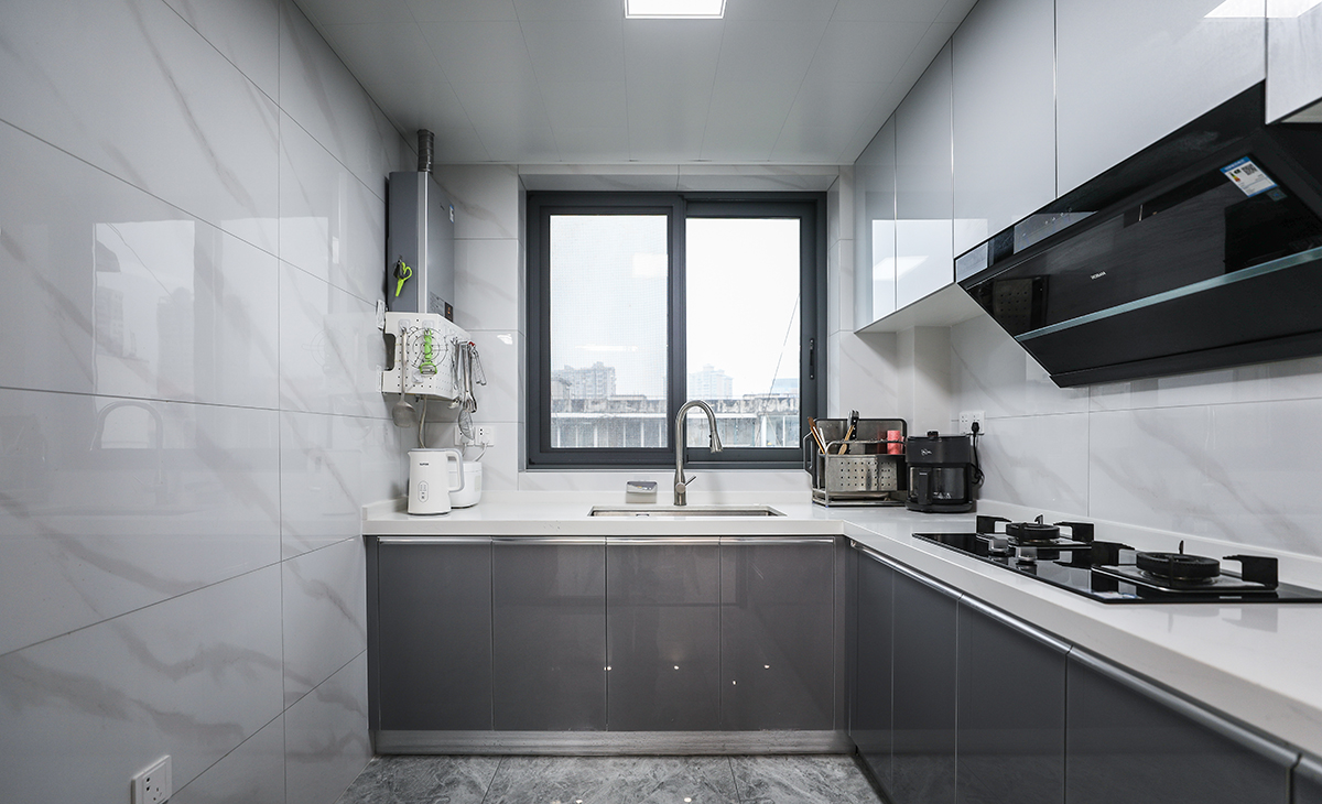 此廚房室L型設計，水槽、切菜，烹飪、等都沿著一條直線或直角排列，這樣的布局既方便了操作，也節省了空間。另外，窗戶的大小也很合理，既保證采光，在視覺感受上也不突兀。色調以黑白為主，線條簡潔，沒有過多的裝飾，看起來非常干凈利落這樣的布局既實用又美觀。