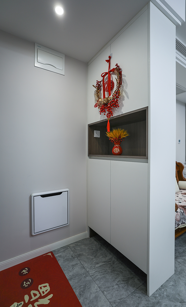 玄關柜功能上在接待客人、換衣、換鞋和放包的功能等，還具有延伸空間的效果。此外，它也可以打造成小平臺，放置小物品如鑰匙，從而增加居家裝飾的趣味性。中國結和裝飾品則懸掛在柜子的上方，這種布局方式不僅突出了紅色元素，還增加了空間的藝術感和層次感玄關在視覺上起到屏障作用，避免開門即看到客廳內部，確保私密性和距離感，特別在家人或朋友來訪時，能有效解決視覺干擾和心理安全問題，使出入過程更加有序。
