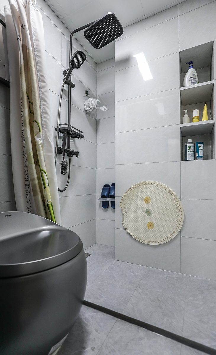 衛(wèi)生間空間不是很大，彩用干濕分離做法，可以滿足干濕區(qū)同時(shí)使用，而不影響到對方，地面淺灰色地磚，白色吊頂，鈦合金移門，配上智能馬桶和電熱毛巾架，更加合理的衛(wèi)浴空間。