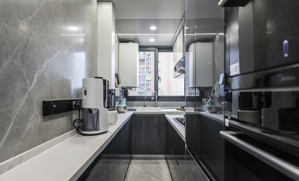 廚房間整體空間不大，業主對操作臺面要求很高，因此兩面都進行了利用，上下櫥柜也選用了上白下灰的拼色處理，空間感覺也更加活躍，臺面選用了2公分的魚肚白石英石，使用起來方便也好打理。