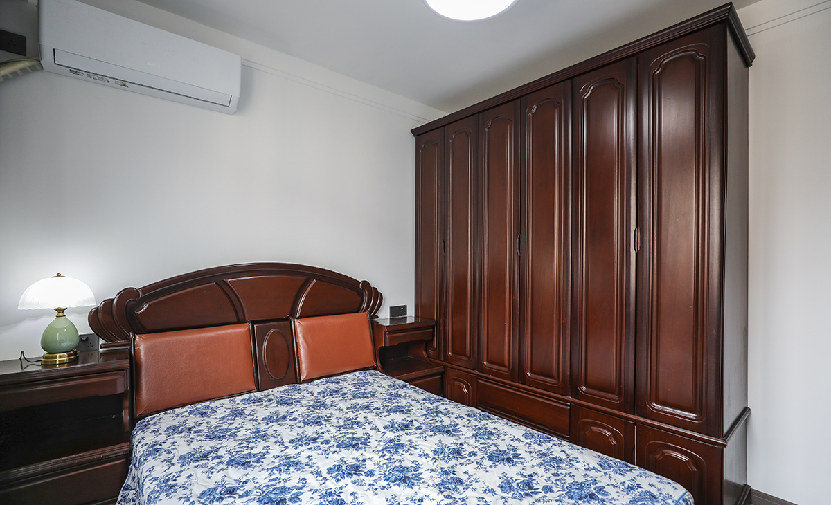 次臥室不做多余的修飾，白墻搭配深色實木家具，厚重富有底蘊。