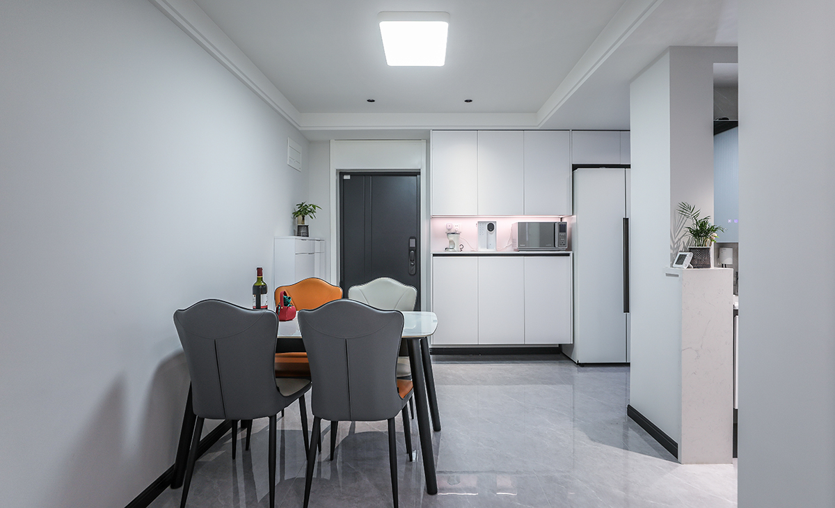 餐廳空間比較方正寬敞，靠入戶門做一排餐邊柜兼鞋柜，既實用、又有裝飾功能，白色框架板及白色門板配黑色踢腳線顏色相互襯托，巖板餐桌把用餐氛圍調和的很溫暖，淺灰色地磚很干凈，色彩和造型上都簡潔大氣。