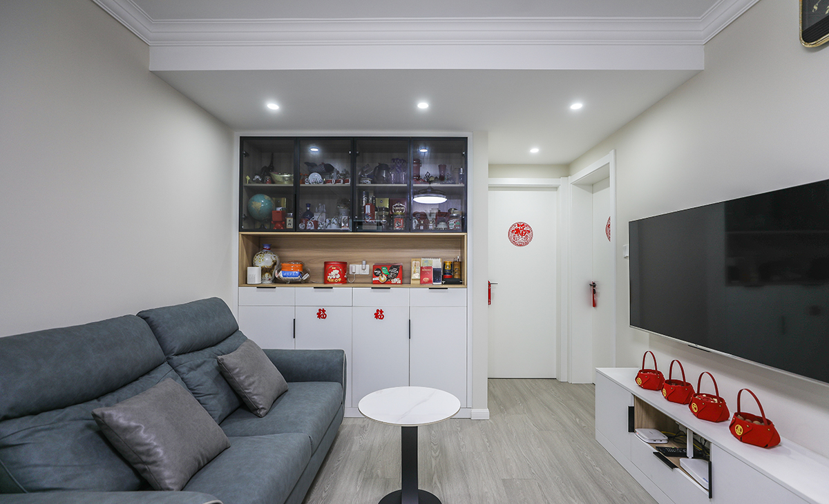 客廳開間并不大，電視墻做淺色乳膠漆，搭配電視矮柜，整體墻面和柜子以淺色系為主，空間感顯得更大，深灰藍色皮質沙發一個是材質高級顯得檔次很高，再有是深色點綴拉出客廳的空間感，層次更多，客廳空間也顯得寬闊。吊頂造型上采用簡單的石膏頂角線處理。地面采用淺灰色地板。造型和色調上無不給人以簡潔、大氣、時尚的感覺。