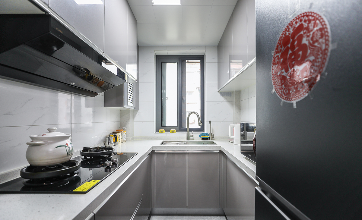 該套房子廚房空間很大，U型兩面櫥柜，另外冰箱邊上也有操作臺，顏色簡潔明快，材質要干凈和好打理，白色的吊頂和灰色的櫥柜相呼應，石英石臺面經久耐用，各種廚房電器全部配齊，滿足主人制作各種美食的需求。