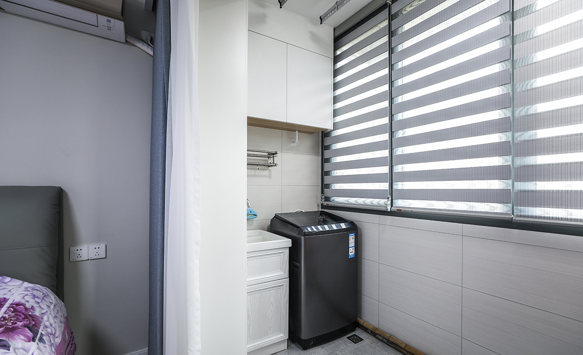 陽臺是晾曬衣物的場所，一側洗衣機和水池，顏色以白色為主，儲物柜白色門板和門套相搭配，超大玻璃窗讓陽光柔和的照進來，很舒適、很愜意。