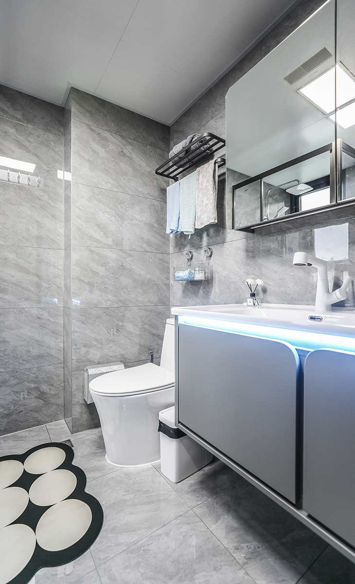 衛(wèi)生間設(shè)計(jì)風(fēng)格簡(jiǎn)約而時(shí)尚，整體色調(diào)以白色和灰色為主，給人一種清新整潔的感覺(jué)。墻磚采用淺灰色，與白色馬桶相得益彰，而洗手臺(tái)上的一條燈帶更加的增強(qiáng)了空間的層次感。