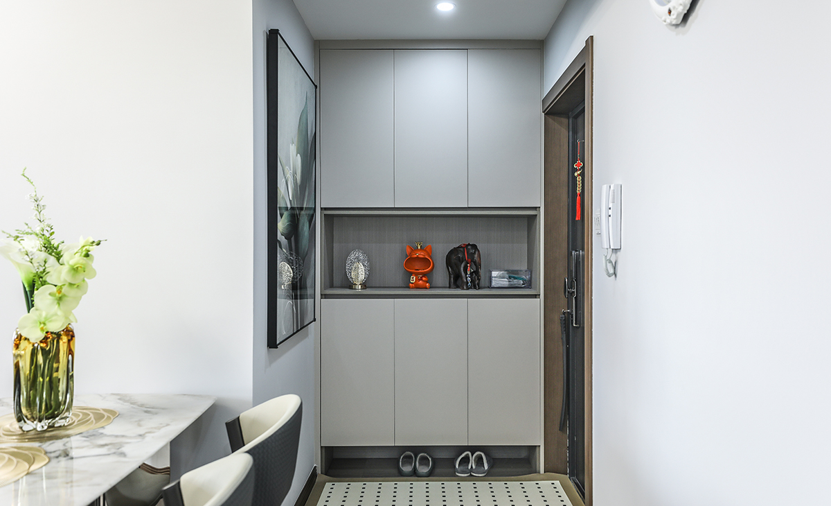 關(guān)柜功能上在接待客人、換衣、換鞋和放包的功能等，還具有延伸空間的效果。此外，它也可以打造成小平臺(tái)，放置小物品如鑰匙，從而增加居家裝飾的趣味性。裝飾物和紅色玩偶放在柜子的中空處，這種布局方式不僅突出了紅色元素，還增加了空間的藝術(shù)感和層次感，同時(shí)進(jìn)門之后是一堵墻，墻面上放置一幅裝飾畫，顏色漂亮獨(dú)特。而且。特別在家人或朋友來(lái)訪時(shí)，能有效解決視覺(jué)干擾和心理安全問(wèn)題，使出入過(guò)程更加有序。