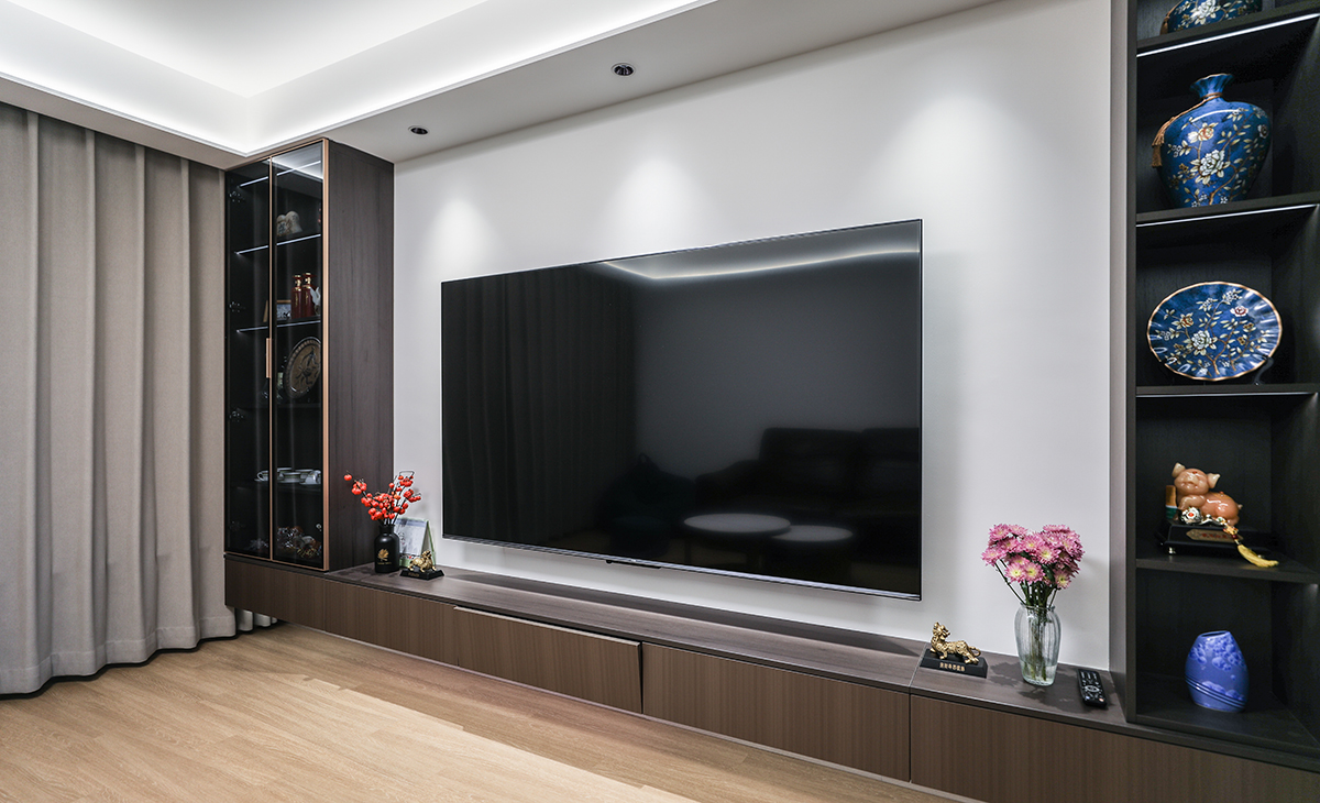 電視墻兩邊做裝飾玻璃柜，中間掛72寸液晶電視。把整面墻點綴地洽到好處，顯得既活潑又時尚，深色電視柜、黑色極窄邊框玻璃門和電視機的色彩相呼應。