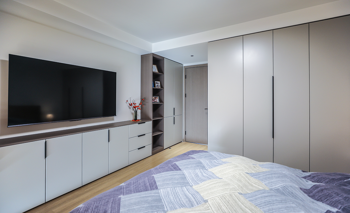 主臥的儲物空間真的很大，門后面一排薄柜+整面電視柜，上方壁掛電視機，墻面乳膠漆和柜門顏色一體，讓整個空間時尚而不凌亂。

