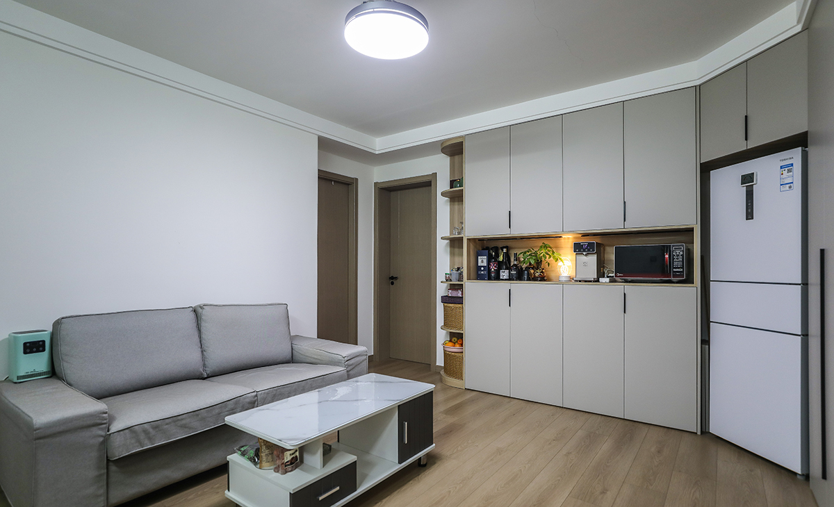 沙發背景刷純白色的涂料，干凈，整潔，清爽。色調上墻面涂料和沙發的深灰色，深淺搭配的錯落有致，既溫馨又簡潔。