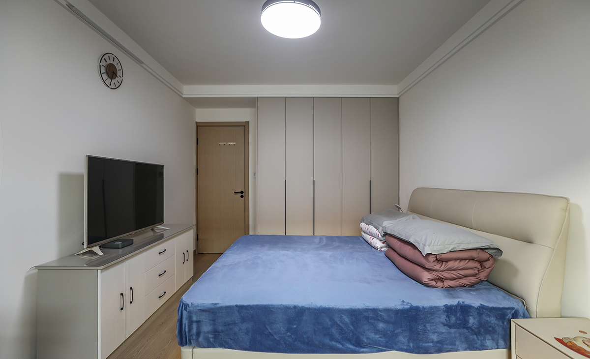 主臥原實木地板，所以床選擇的是暖灰色，衣柜門板也是暖灰色，這樣和地板進行搭配，非常的和諧、整體。頂面圓型吊扇燈，實現方中有圓，圓中有方，造型以簡潔平板為主，方便打理，體現了簡約風格的簡潔、隨意，不拘一格。