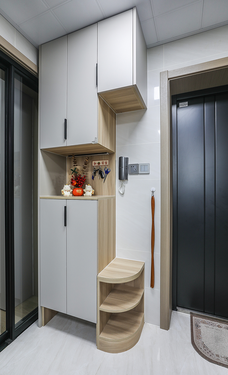 進門鞋柜做成上下柜，中間落空，平時汽車鑰匙，小包都可以擺放。邊上做一個離地45公分高的下柜，再也不用站著換鞋。還做了倒圓處理，節約了空間，還防止進出磕碰。