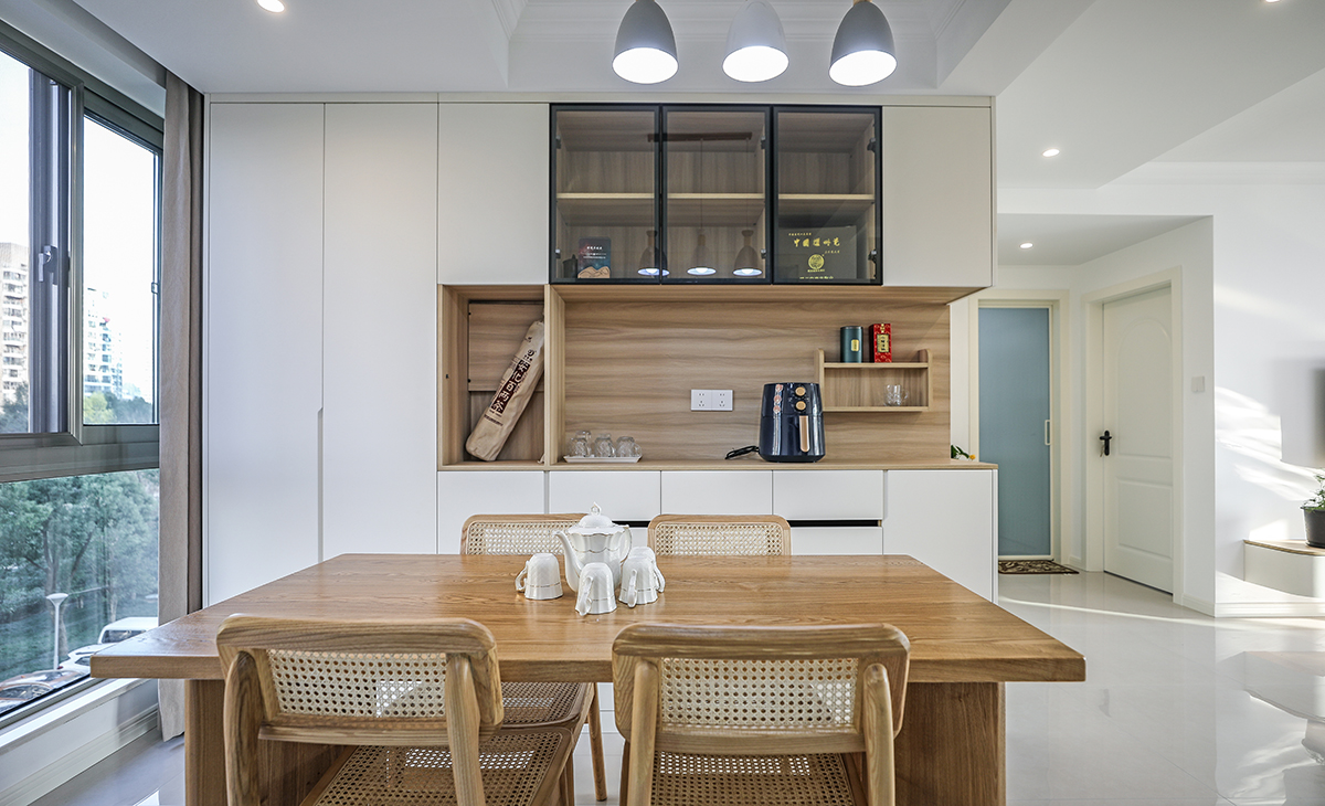 原木色餐廳餐桌搭配餐邊柜，既實用、又有裝飾功能，頂上吊燈增加氛圍感，地面同客廳地磚通鋪，整體色彩和造型上都簡潔大氣舒適。