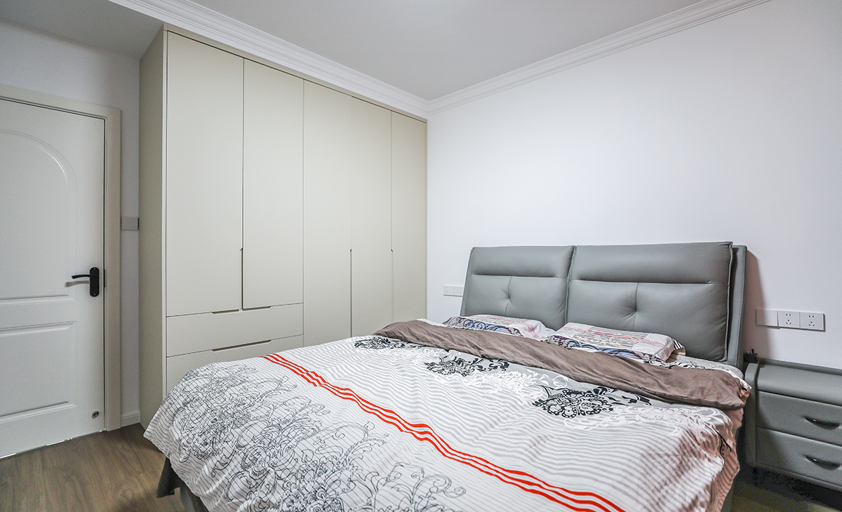 主臥增加儲藏，既美觀又實用，顏色上深淺搭配地錯落有致，橡木色地板，墻面暖白色干凈清爽，頂面白色乳膠漆，輕巧時尚的吸頂燈，空間很溫馨和諧。