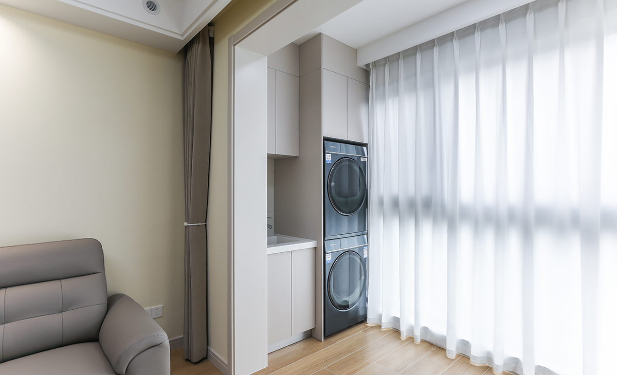 陽臺是晾曬衣物的場所，一側洗衣機和水池，上方為儲物柜，顏色以羊絨灰為主，和門套相配，大玻璃窗讓陽光柔和的照進來，很舒適、很愜意。