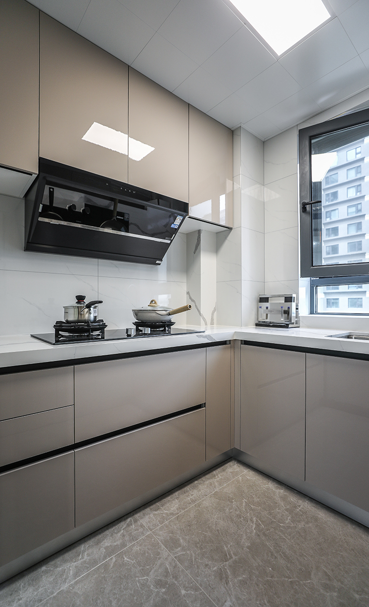 該套房子廚房空間較大，U型三面櫥柜，采用高光pet門板，顏色簡潔明快，材質干凈和好打理，白色的吊頂和米色的上、下櫥柜相呼應，石英石臺面干凈、好打理，各種廚房電器全部配齊，滿足主人制作各種美食的需求。